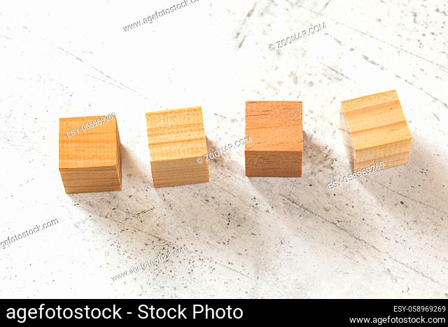 Four blank wooden cubes on white cement board