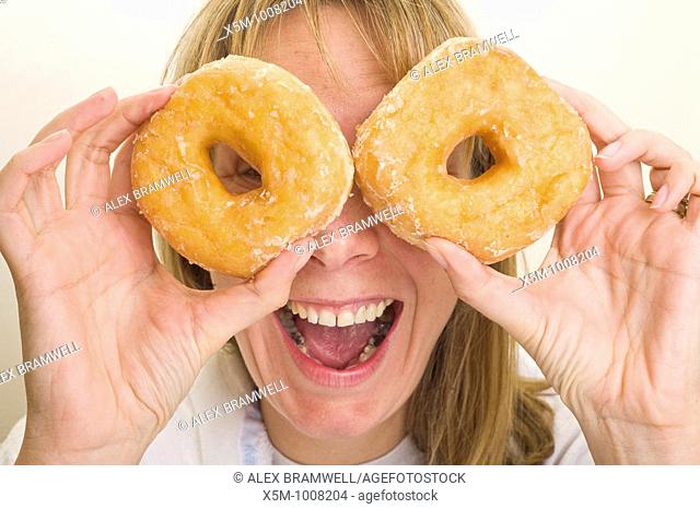 Woman holding donuts up in front of her eyes