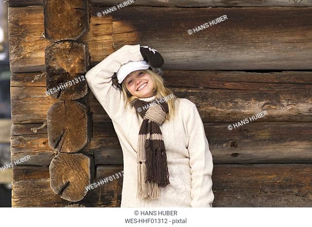 Young woman leaning on wooden wall