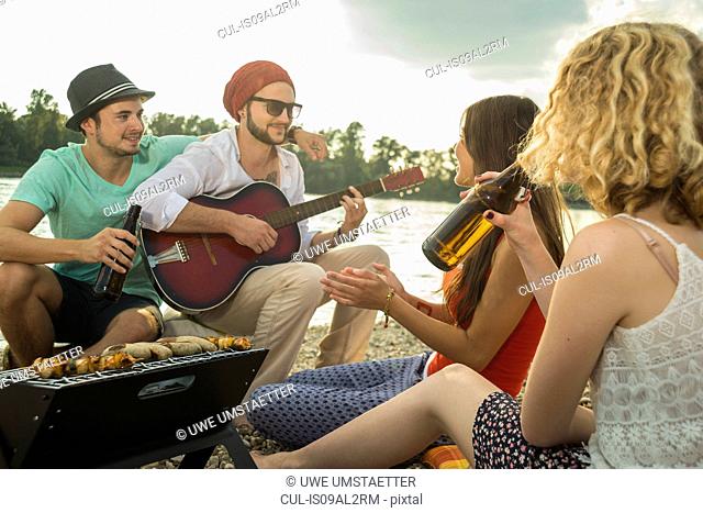 Young man with friends playing guitar