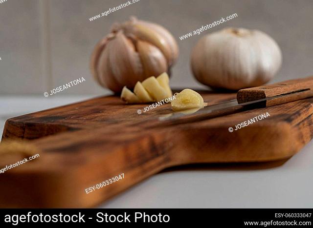 whole and peeled garlic on wooden board and white background