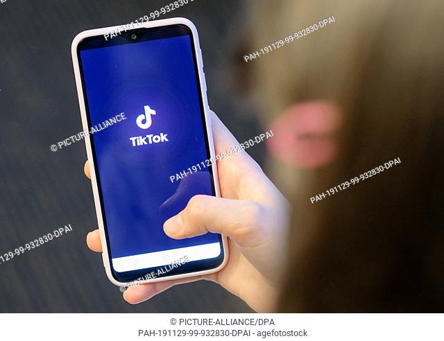13 November 2019, Berlin: ILLUSTRATION - A girl is holding her smartphone with the logo of the short video app TikTok in her hands
