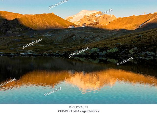 The rocky peaks are reflected in the alpine lake at sunset, Stelvio Pass, Valtellina, Lombardy, Italy, Europe