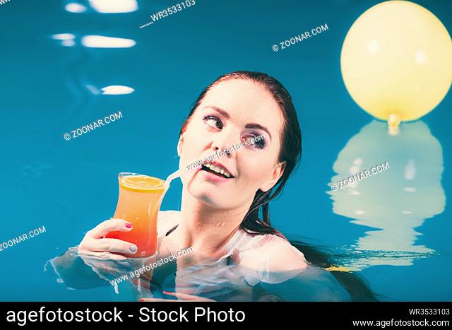 Happy woman cocktail drink alcohol in swimming pool water. Pretty attractive girl relaxing