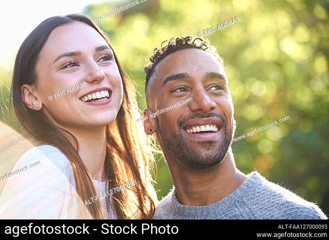 Close-up of smiling young couple looking away in public park