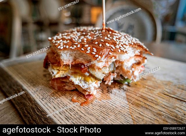 Bited Burger. American snack with big hamburger on wooden plate