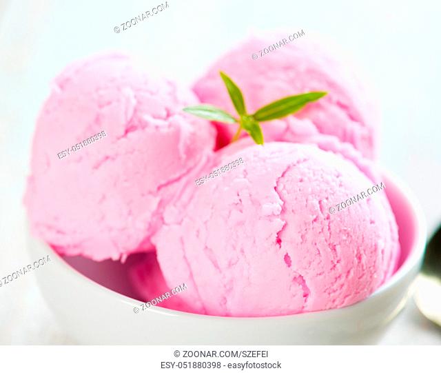 Pink berry ice cream in bowl on white wooden background