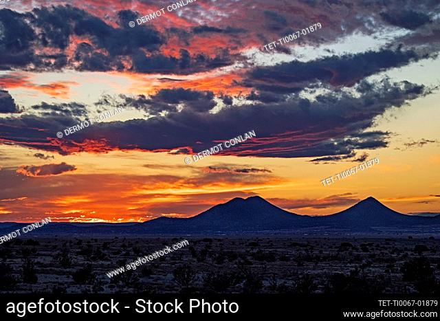 USA, New Mexico, Santa Fe, Cloudy sky over desert landscape at sunset