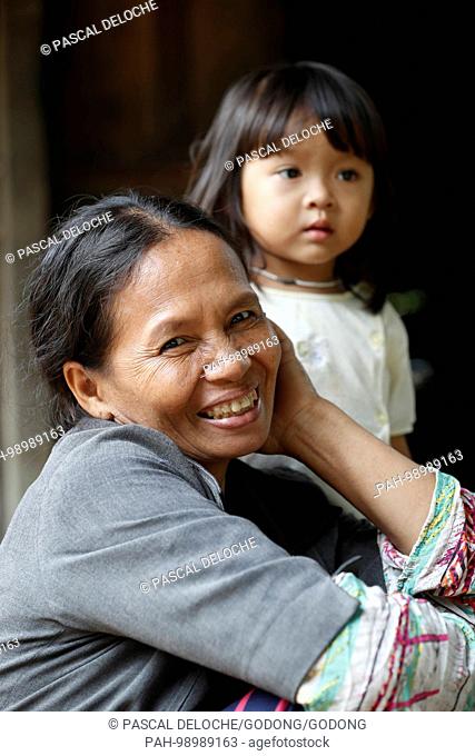Bahnar (Ba Na) ethnic group. A smiling woman and her daughter inside their traditional home. Kon Tum. Vietnam. | usage worldwide