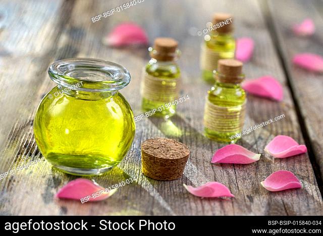 Rose flower petals with aromatherapy essential oil glass bottle isolated on wooden, background, copy-space