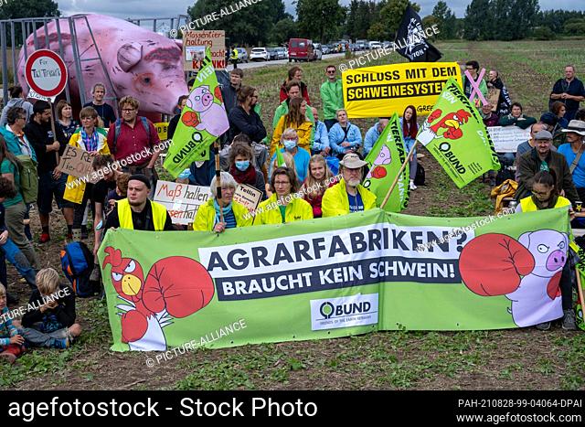 28 August 2021, Mecklenburg-Western Pomerania, Alt Tellin: Animal and environmental activists demand an end to factory farming with a poster reading...