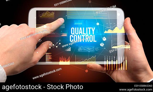 Close-up of hands holding tablet with QUALITY CONTROL inscription, modern business concept