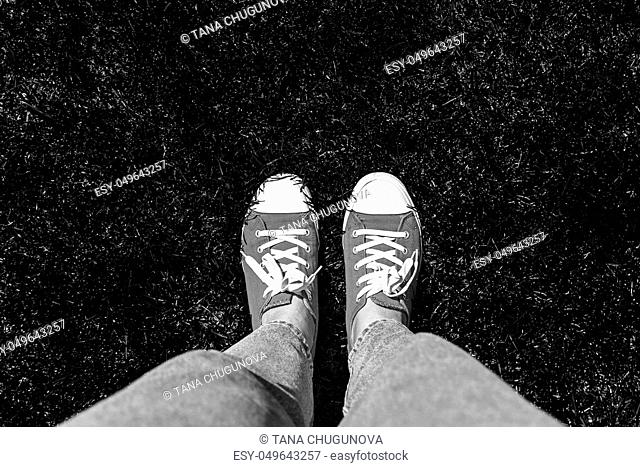 Legs in old sneakers on grass. View from above. Style: abstraction, illustration, monochrome, neon