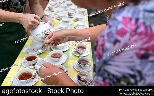 29 July 2023, Lower Saxony, Leer: Two employees of the tea museum pour tea the East Frisian way. Record attempt at the Bünting Tea Museum: serving 200 cups of...