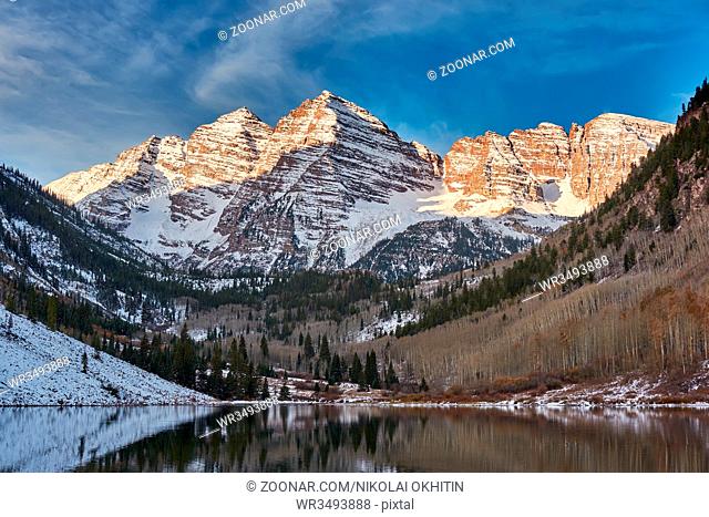 Maroon Bells and Maroon Lake with reflection of rocks and mountains in snow around at autumn in Colorado Rocky Mountains, USA