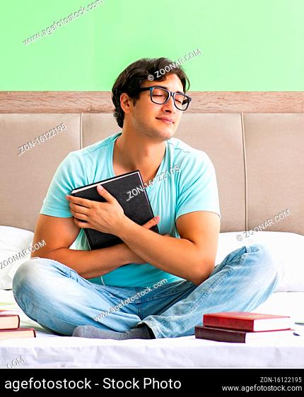 Student preparing for exams at home in bedroom sitting on the bed