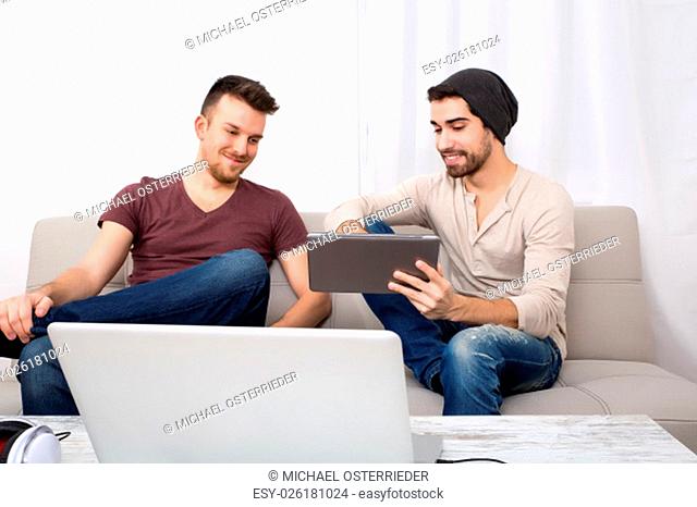 Two young men using a tablet pc at home