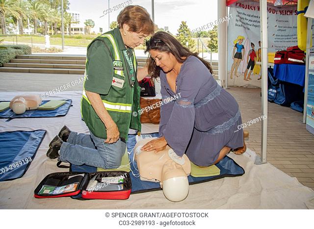 Using a dummy, a woman gets a cardiopulmonary resuscitation (CPR) lesson from a uniformed CERT (Community Emergency Resource Team) volunteer at a health...