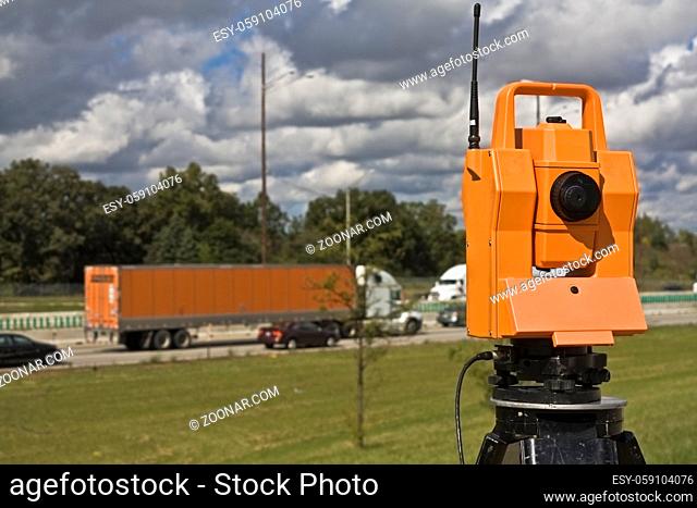 Survey on the highway - orange theodolite and semi-truck