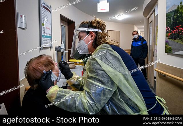13 January 2021, Saxony-Anhalt, Sangerhausen: Sindy Siegmund, geriatric nurse, tests a visitor at the entrance to the DRK nursing and care centre ""Tor zur...