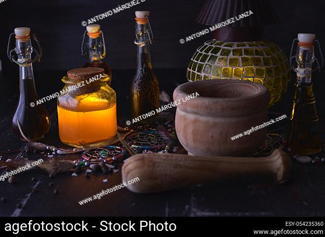 Magic luminous alchemy potions, old lantern on dark background over black wood with an Indian amulet