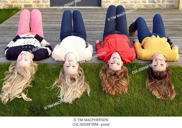 Four teenage girls lying on patio and looking back