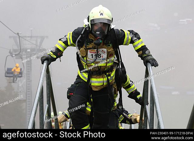 01 April 2023, Thuringia, Oberhof: Firefighters run up the stairs of the Lotto Thüringen ski jump in protective suits and compressed air breathing apparatus...