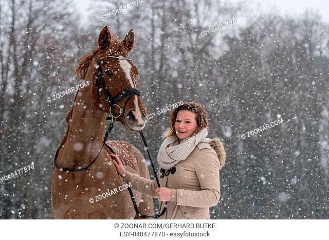 Junge Frau mit ihrem Pferd im Schneegestöber