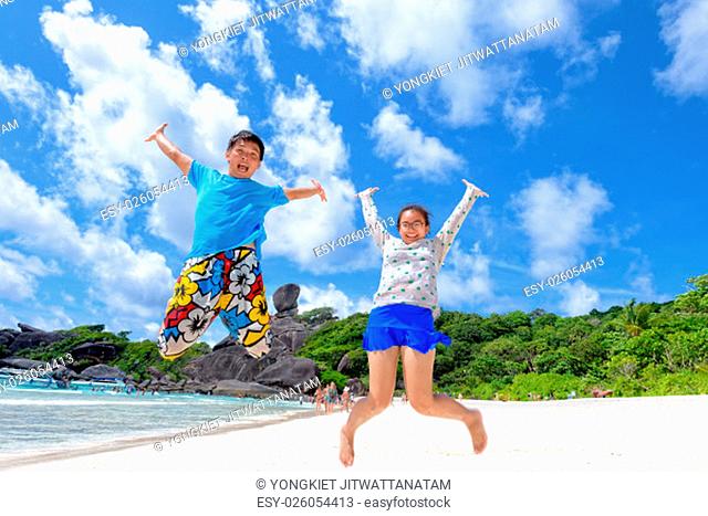 Father and daughter jumping with happy on beach near the sea under blue sky and cloud of summer at Koh Similan Island in Mu Ko Similan National Park