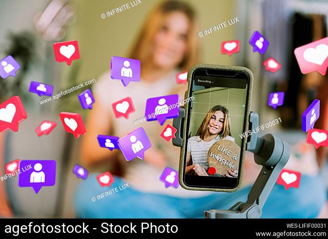 Smiling teenage girl on mobile phone screen amidst social media icons at home