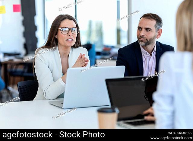Businesswoman wearing eyeglasses discussing strategy with colleagues in office