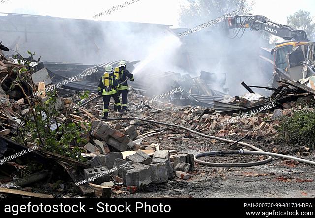 30 July 2020, Mecklenburg-Western Pomerania, Ribnitz-Damgarten: Firefighters extinguish the fire in a large hall of a former furniture manufacturer