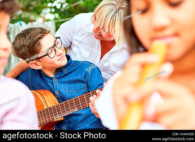 Lehrer hilft Kind mit Gitarre beim Musikunterricht im Ferienlager oder Sommercamp