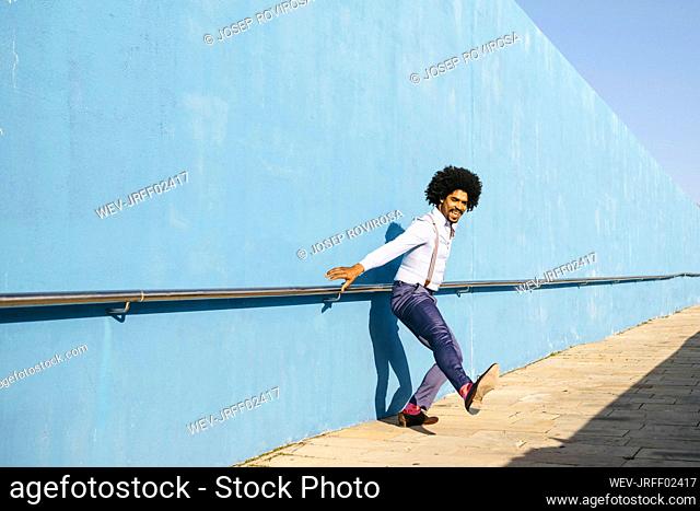 Man dancing in front of blue wall