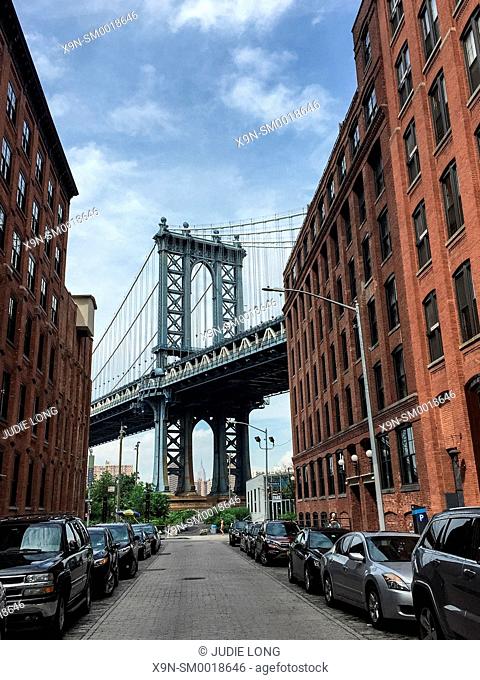 Manhattan Bridge, seen from the streets of the Dumbo neighborhood of Brooklyn, NY. Empire State Building in Manhattan, visible through the bottom opening of the...