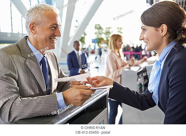Customer service representative helping businessman at airport check-in counter