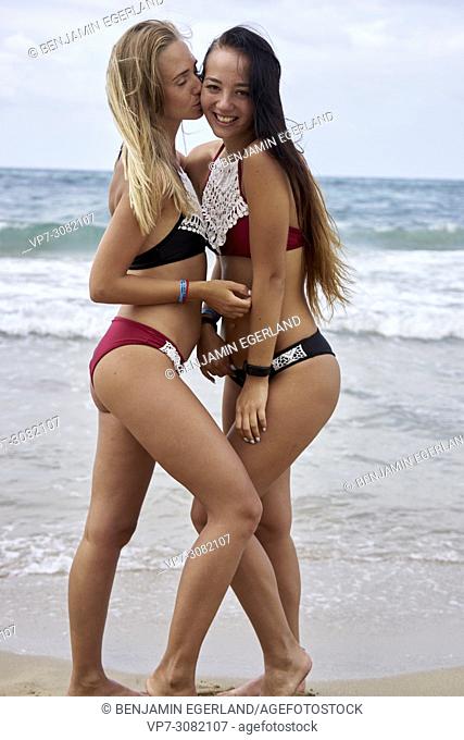 women kissing best friend at beach, wearing bikini, feeling sexy, arm around shoulder, bonding. Greece, Crete, Malia