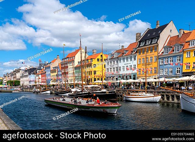 Copenhagen, Denmark - 13 June, 2021: view of the historic Nyhavn quarter in downtown Copenhagen with a tourist boat cruise barge in the foreground