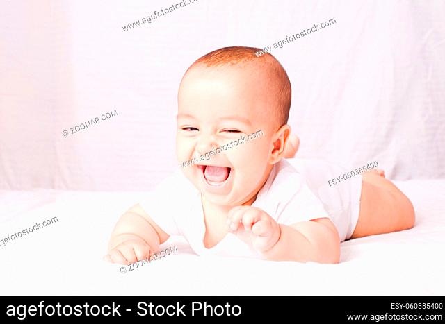 Courious baby lying on the stomach and laughing