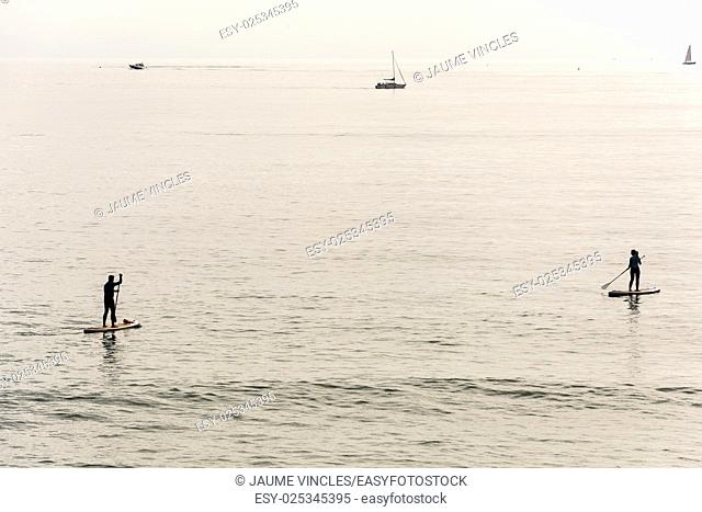 Couple practicing surf paddle on the Barcelona Coast