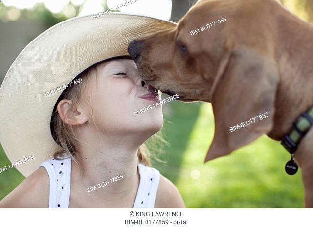 Caucasian girl kissing dog outdoors