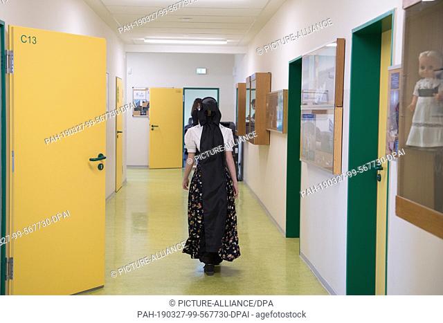 27 March 2019, Saxony, Ralbitz: A schoolgirl in a Sorbian costume walks along a corridor in the secondary school in Ralbitz