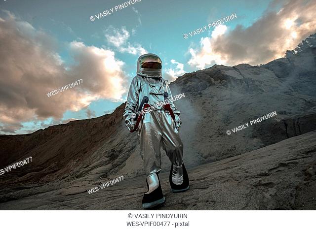 Spaceman exploring nameless planet, walking in a dust cloud