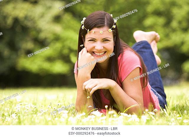 Woman lying outdoors with flowers smiling