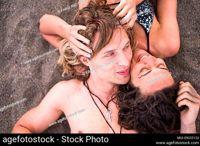 Caucasian young couple lay down together on the beach viewed from the top have fun and love in friendship and relationship enjoying the summer time with laugh...