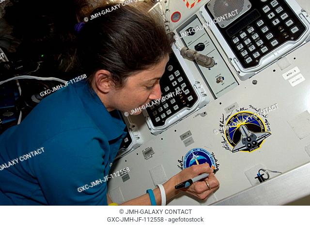 NASA astronaut Nicole Stott, STS-133 mission specialist, signs the STS-133 patch, which was added to the growing collection of insignias representing crews who...