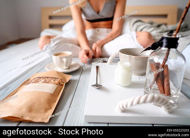 Woman eating cereals in bed, light background