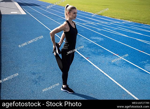 Sportswoman stretching leg on track