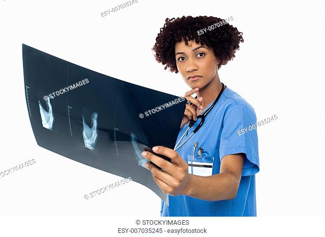 Expression of thoughtful female doctor holding x-ray sheet over white background