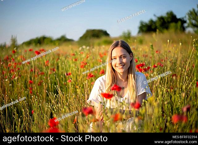 Smiling young woman in poppy field